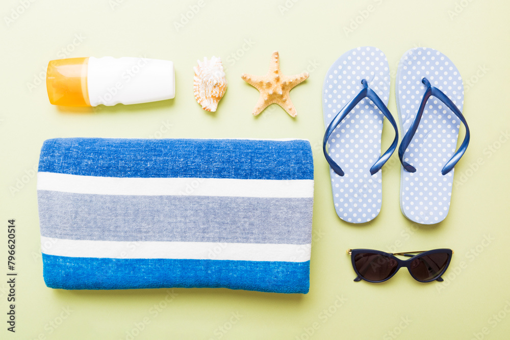 Summer holiday concept. Top view of beach towel, flip flop and sunscreen cream on table Top view with copy space for text - obrazy, fototapety, plakaty 