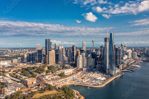 Aerial view modern skyscrapers and buildings against near ocean and cloudy sky. Sydney, Australia. © romankrykh