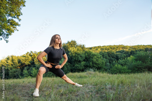 The girl is playing sports outdoors. Athletic girl in a tight uniform working outdoors in the park.