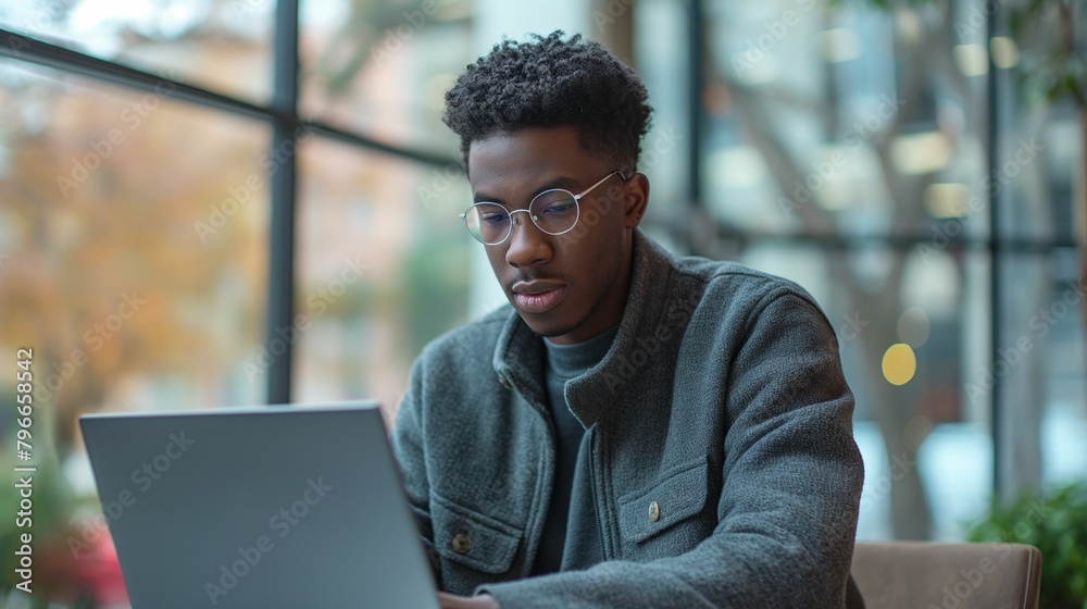 Studious Young African American, Modern Eyewear, Concentrating in Bright Workspace Studious Young African American, Modern Eyewear, Concentrating in Bright Workspace