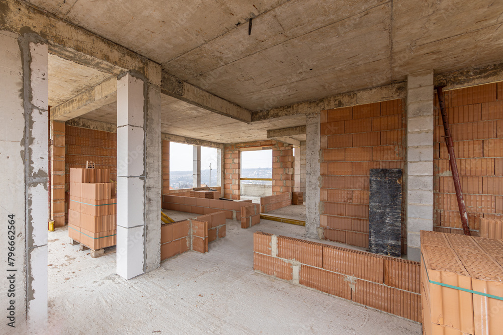 Unfinished room interior of house under construction. Brick red walls. New home. Unfinished room interior of house under construction. Brick red walls. New home.
