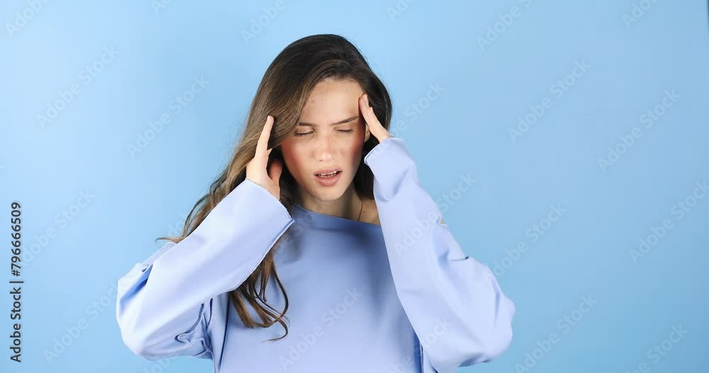 Attractive woman close up with strong headache. Beautiful young brunette touching her temples feeling stress or pain. Stress or headache concept. Negative human emotion isolated on blue background. Attractive woman close up with strong headache. Beautiful young brunette touching her temples feeling stress or pain. Stress or headache concept. Negative human emotion isolated on blue background.