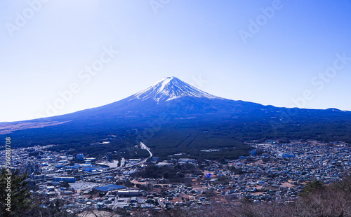 Look pass village and landscape city at Mount Fuji world famous tourist attractions. Beautiful mountain with snow and white fog cover on top with bright blue sky, bright is background.