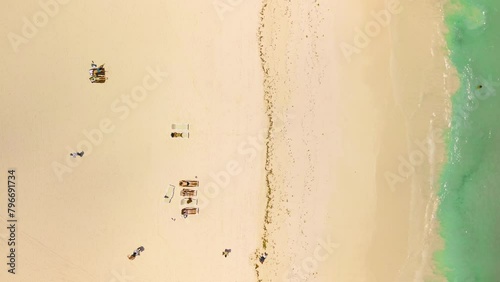 Top down aerial view golden beach with turquoise water. Tourists relax on sun loungers. Minimalism photo