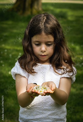 Portrait of a girl holding daisies in her palms on a summer day.