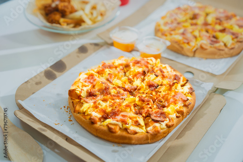Savor a delicious slice of Italian pizza, baked to perfection with mozzarella, ham, pineapple, and pepperoni. Enjoy it at a rustic restaurant or homemade at your kitchen table.
