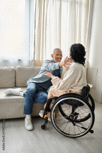 A man and a disabled woman hugging each other affectionately in a cozy living room.
