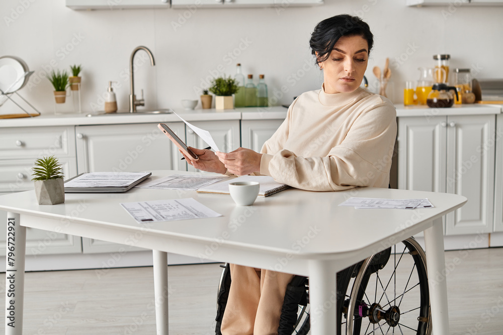 A disabled woman in a wheelchair works remotely using a tablet at her kitchen table. A disabled woman in a wheelchair works remotely using a tablet at her kitchen table.