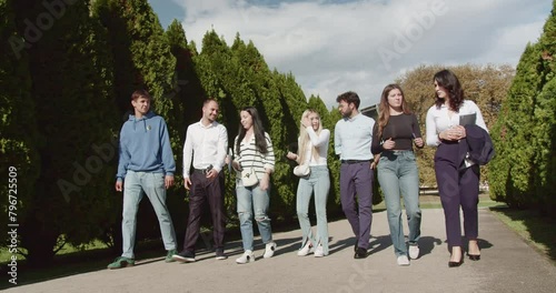 Accomplished college students stroll and discuss in a park, epitomizing camaraderie and campus life amid lush greenery under the sunny skies, capturing the spirit of academic success.