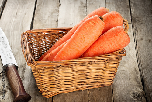 Peeled sweet carrots in a basket on a wooden table.