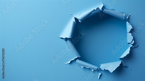 Bright blue wall with a large, irregular hole revealing a darker blue background photo