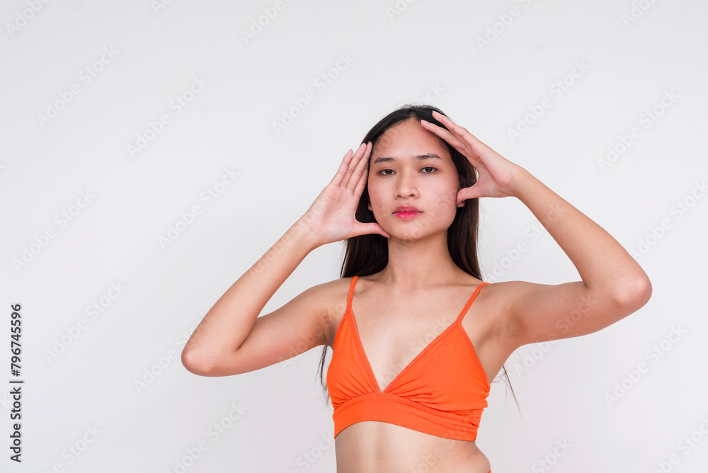 Young Asian woman in orange bralette posing with hands on her head, isolated on white Young Asian woman in orange bralette posing with hands on her head, isolated on white