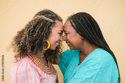 Happy african mother and adult daughter having tender moment together while wearing traditional clothes - Family love concept - Neutral background