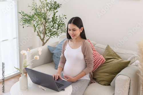 Pregnant woman working on laptop and smart phone in the living room at home