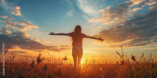 woman with her arms in the air, enjoying freedom in the sunset in a field 