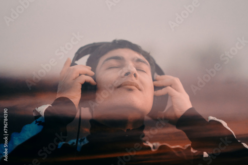 Chico disfrutando de la música con sus auriculares, doble exposición photo