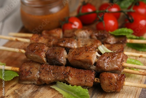 Tasty cooked marinated meat served with sauce and tomatoes on table, closeup