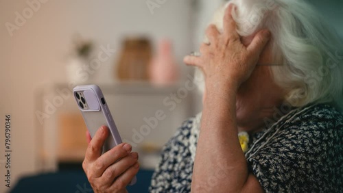 Funny grandmother in glasses shocked by a video with indecent content on phone photo