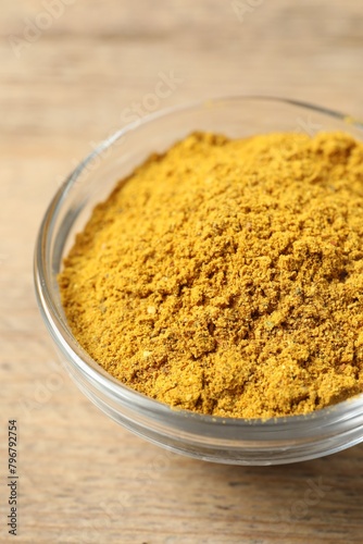 Curry powder in bowl on wooden table, closeup © New Africa