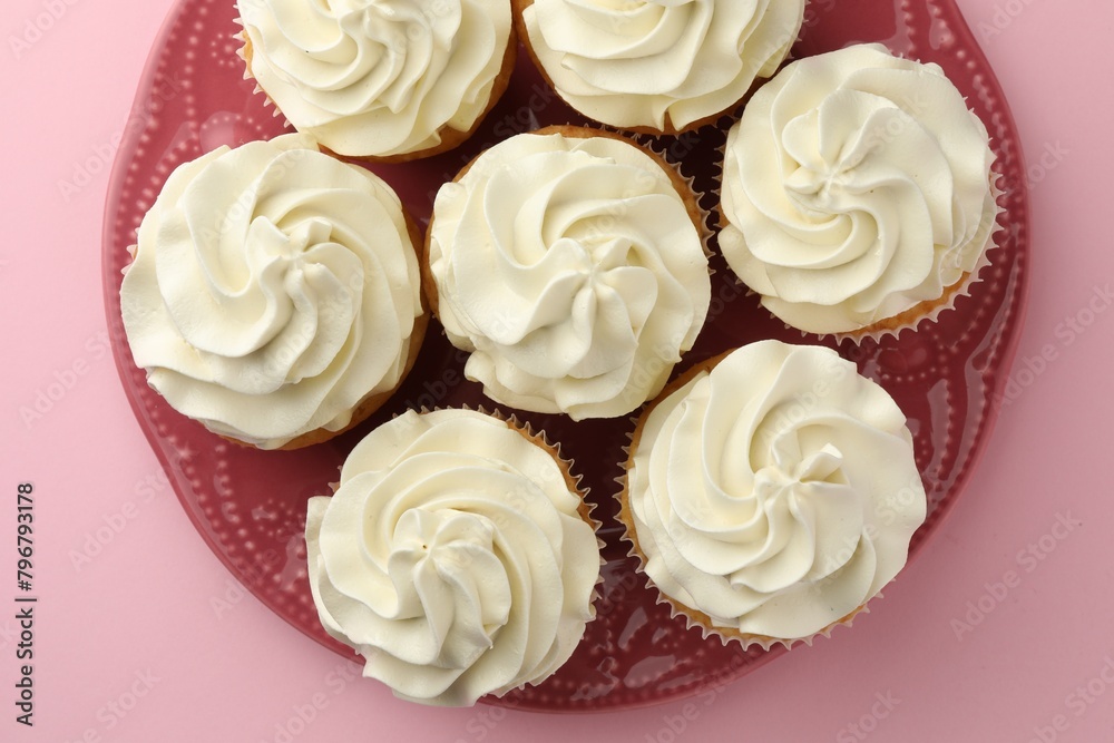 Tasty vanilla cupcakes with cream on pink background, top view Tasty vanilla cupcakes with cream on pink background, top view