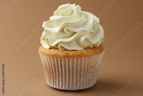 Tasty vanilla cupcake with cream on dark beige background, closeup