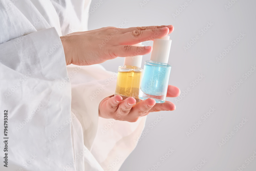 Two yellow and blue serums in a womans hands in a robe. Two yellow and blue serums in a womans hands in a robe.