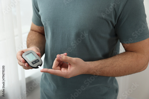 Diabetes test. Man checking blood sugar level with glucometer at home, closeup