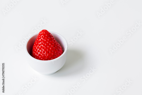 Single strawberry in a white bowl, emphasizing simplicity and health