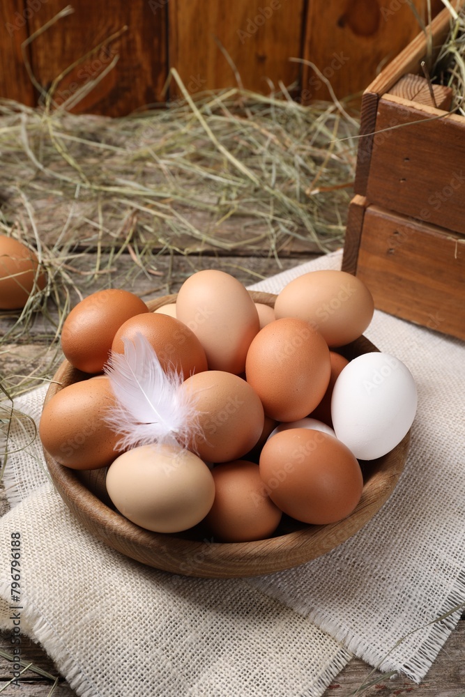 Fresh chicken eggs in bowl and dried hay on wooden table Fresh chicken eggs in bowl and dried hay on wooden table