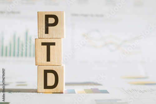 Wooden Blocks Stacked to Spell PTD Against Graph Background in Office Environment