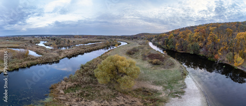Aerial tree growing on river curve panorama with autumn forest and grey cloudy sky in Ukraine