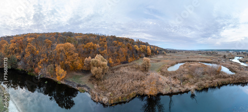 Aerial golden autumnal river panorama with autumn forest and scenic cloudscape