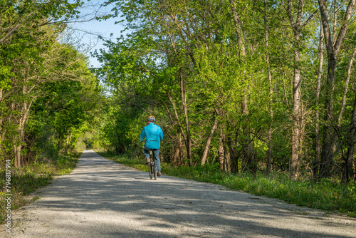Male cyclist is riding a folding bike on Katy Trail near Rocheport, Missouri, spring scenery. The Katy Trail is 237 mile bike trail converted from an old railroad. photo