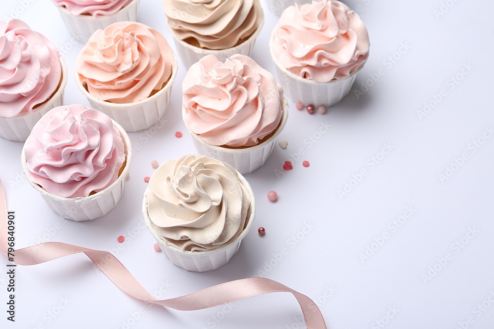 Many tasty cupcakes, sprinkles and ribbon on white background Many tasty cupcakes, sprinkles and ribbon on white background