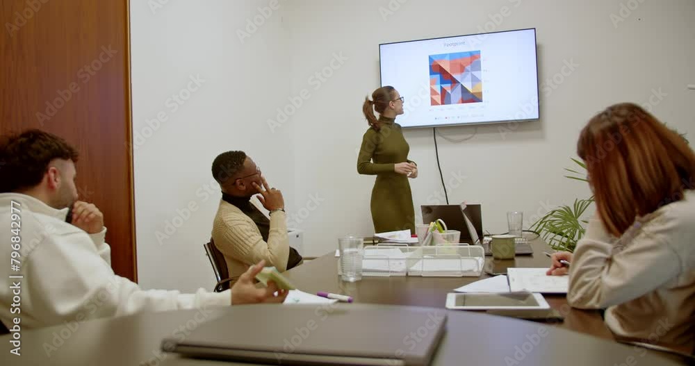 In a meeting room, a diverse business team analyzes strategy and growth, engrossed in a presentation, highlighting their commitment to success and collaborative approach.