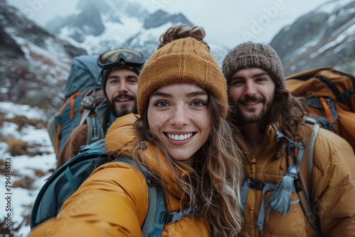 A selfie of three people in winter gear, with snow-covered mountains in the background