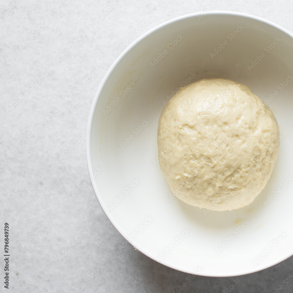 Coco bread dough rising in a white mixing bowl, process of making jamaican coco bread