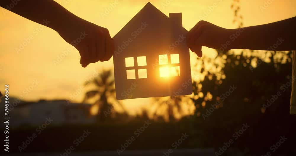 Dream buy house. Paper house hands family, sun shines in window close-up. Hands, paper house at sunset. Symbol home, family comfort. Concept building house family, child. Real estate insurance
