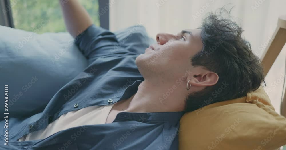 A young man takes a moment to rest on a couch, exhibiting signs of fatigue while working from home, embodying the challenges of remote entrepreneurship. A young man takes a moment to rest on a couch, exhibiting signs of fatigue while working from home, embodying the challenges of remote entrepreneurship.