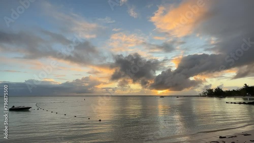 The beautiful yellow sunset on the island of Mauritius in summer with numerous clouds and great weather. In the foreground you can see the sea with a small ship.