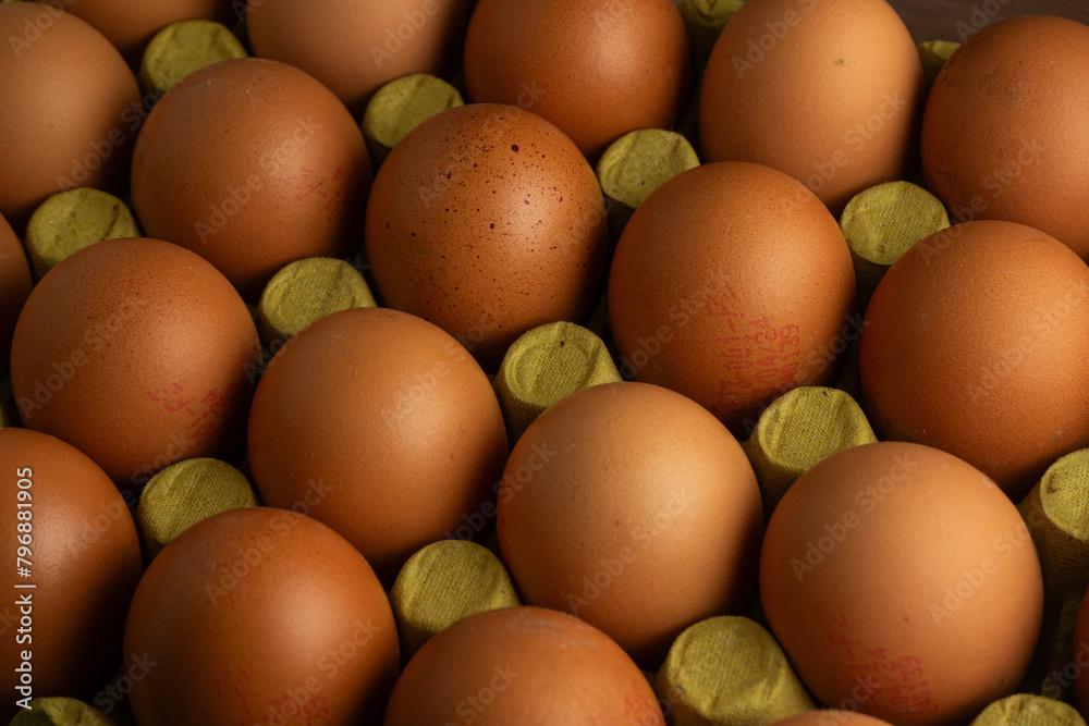 A neatly arranged row of brown chicken eggs in a cardboard carton. The eggs are evenly spaced, highlighting their uniformity. The soft light casts gentle shadows, creating a warm, inviting atmosphere. A neatly arranged row of brown chicken eggs in a cardboard carton. The eggs are evenly spaced, highlighting their uniformity. The soft light casts gentle shadows, creating a warm, inviting atmosphere.