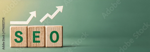 Wooden blocks with SEO letters and arrows going up on solid green background showing search optimization engine success of website, blog, shop in internet business ranking. Banner with opy space