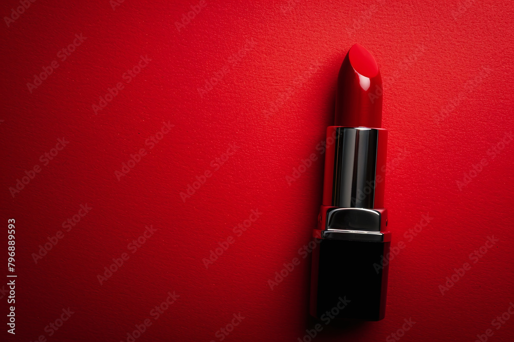 Red lipstick on a vivid red background with copy space. Cosmetics banner concept, top view, flat lay. Minimal and luxury make up cosmetic or beauty salon composition banner