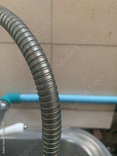 water tap, Shower head and hose with ceramic wall background, closeup of photo, The shower hose is made from threaded stainless steel.