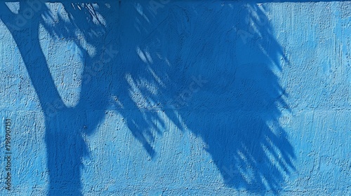   A person casting a shadow, holding a tennis racket, before a blue wall Shadow of a palm tree adjacent photo