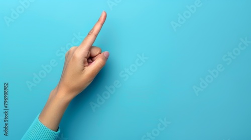   A woman's hand, index finger pointed left, against a blue background Copied Up space available photo