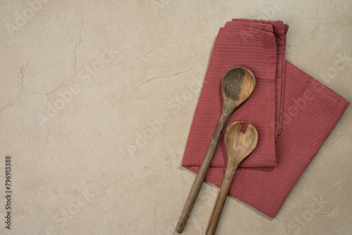 Background with burgundy kitchen towel and wooden spoons, stone table, cooking