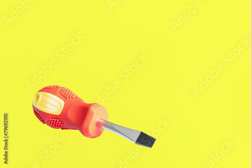 A screwdriver. A working tool. A flat screwdriver on a yellow background. Copy space