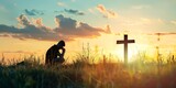 a person kneeling in a field with a cross in the background at sunset or dawn with a person kneeling in the grass