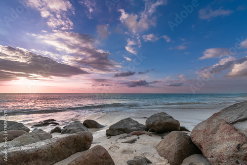 Tropical beach with rocks and blue waters and pink sunset in Antigua